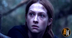  A young woman with auburn hair and wide, frightened eyes peers around a tree in a dark forest. She wears a dark jacket, her expression tense and watchful. Cool blue-green light creates an eerie, unsettling atmosphere.