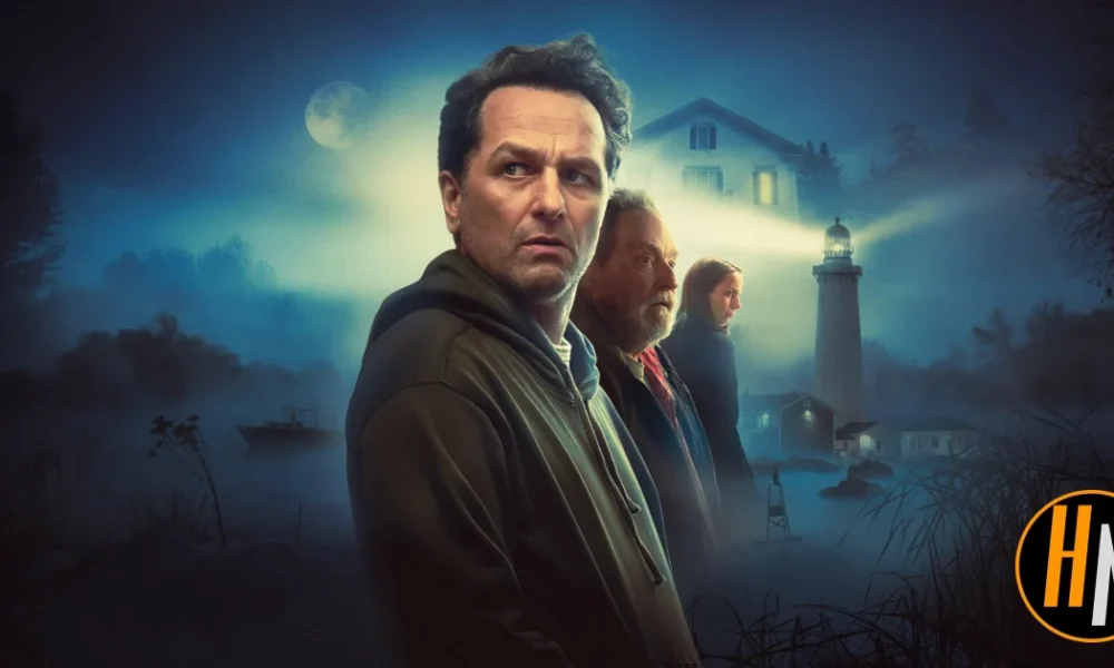 Promotional image for the Apple TV+ series Widow's Bay. A man in a dark hoodie stands in the foreground, looking wary, with an older man and a young woman behind him. A misty coastal scene surrounds them, featuring a lighthouse beam cutting through fog, a house with lit windows, and a small boat on dark water under a full moon. The Horrortainment News logo appears in the lower right corner.